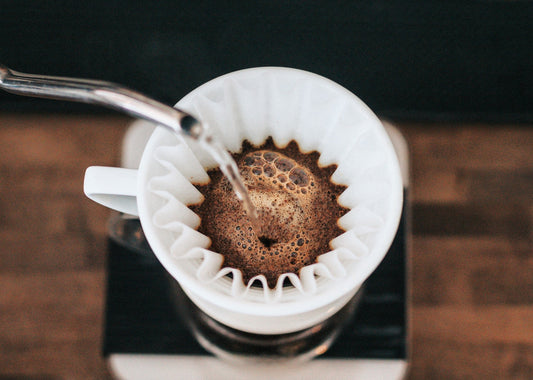 Filterkoffie zetten: warm water wordt over vers gemalen koffie geschonken in een filter voor een perfecte kop koffie thuis